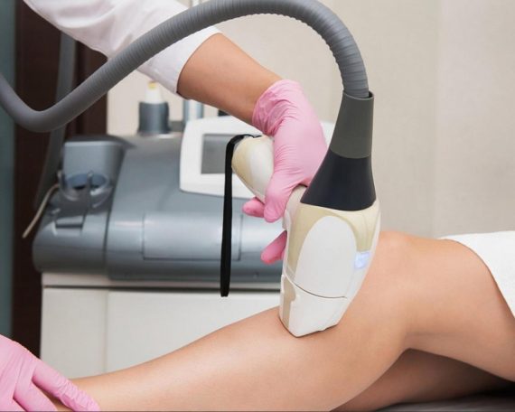 Aesthetician performing a laser resurfacing treatment on a patient's leg in a UAE clinic